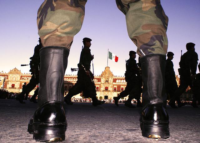 Soldaten auf einem Platz. Im Hintergrund die mexikanische Fahne