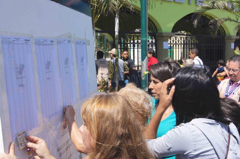 Vor den Wahlbüros informieren sich die Wählerinnen und Wähler anhand ihrer Ausweisnummer, an welchem Wahltisch sie ihre Stimme abgeben können.