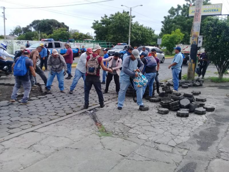 Nach der Beseitigung einer mit Pflastersteinen errichteten Straßenblockade reparieren Anwohner eine Straße in Managua, Nicaragua