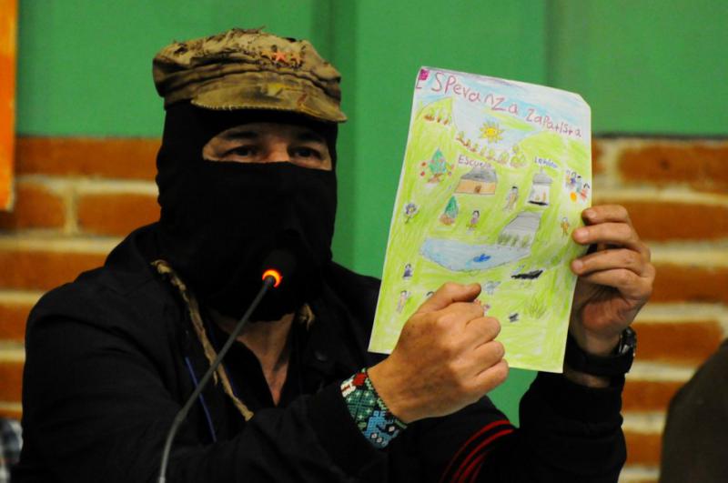 Galeano zeigt die Zeichnung eines zapatistischen Mädchens für die Angehörigen der 43 verschwundenen Lehramtsstudenten aus Ayotzinapa Galeano zeigt die Zeichnung eines zapatistischen Mädchens für die Angehörigen der 43 verschwundenen Lehramtsstudenten aus Ayotzinapa
