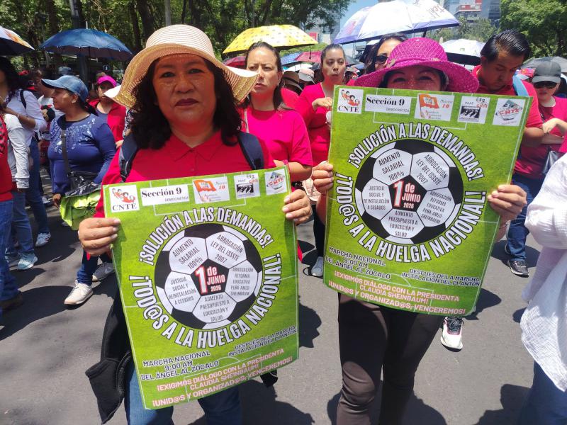 Zwei Lehrerinnen aus Chiapas protestieren mit Plakaten, auf denen ihre Forderungen in einen Fußball eingeschrieben sind