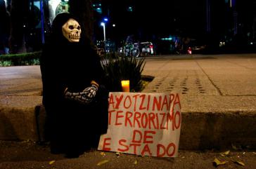 Demonstrant mit Totenkopfmaske und Transparent: "Ayotzinapa - Staatsterrorismus"