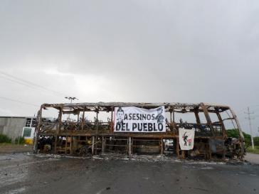 Straßensperre mit ausgebranntem Bus. Auf dem Transparent: "Mörder des Volkes" mit den Konterfeis von Präsident Peña Nieto und Innenminister Osorio Chong