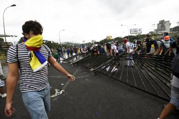 Demonstrant vor der Militärbasis Carlota in Venezuela mit ausgerissenem Gitter