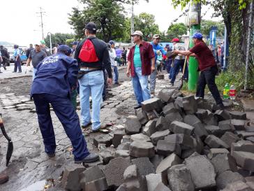 Nach der Räumung von Straßensperren reparieren Gemeindearbeiter und Bürger gemeinsam eine Straße in Masaya, Nicaragua