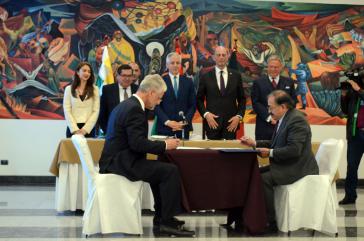 Bolviens Vizepräsident García Linera und Thüringens Wirtschafts- und Wissenschaftsminister Tiefensee (stehend hinten) bei der Unterzeichnung des Vertrages