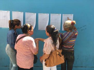 Venezolanerinnen überprüfen vor einem Wahlzentrum ihre Ausweisnummer, um das für sie vorgesehene Wahllokal zu finden