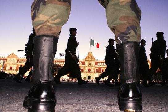 Soldaten auf einem Platz. Im Hintergrund die mexikanische Fahne