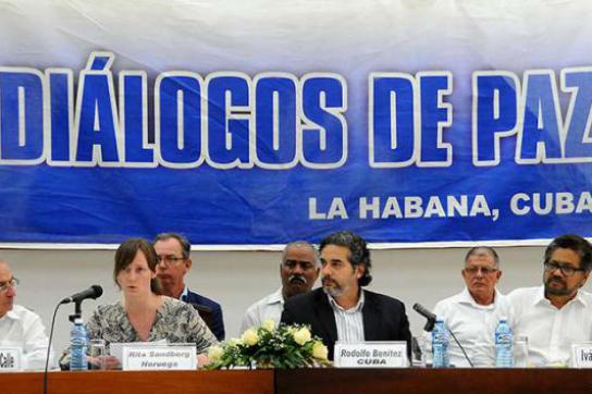 Rita Sandberg (Norwegen) und Rodolfo Benitez (Kuba) verlasen das Dokument. Neben ihnen die Leiter der Friedensdelegationen der Regierung Kolumbiens, Humberto de la Calle (links) und der Farc, Iván Márquez