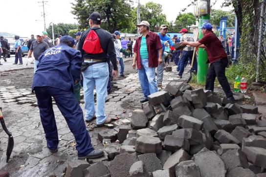 Nach der Räumung von Straßensperren reparieren Gemeindearbeiter und Bürger gemeinsam eine Straße in Masaya, Nicaragua